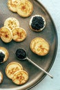 Blinis with black caviar and cream cheese, shot from above on a festive dish