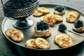 Blinis with black caviar, on a festive dish on a black background, mini pancakes