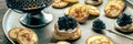 Blinis with black caviar panorama. Mini pancakes on a festive dish