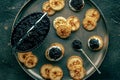 Blinis with caviar, overhead flat lay shot on a festive dish, mini pancakes