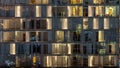 Windows of the multi-storey building of glass and steel lighting inside and moving people within Royalty Free Stock Photo