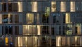 Windows of the multi-storey building of glass and steel lighting inside and moving people within Royalty Free Stock Photo