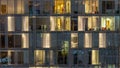 Windows of the multi-storey building of glass and steel lighting inside and moving people within Royalty Free Stock Photo