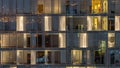 Windows of the multi-storey building of glass and steel lighting inside and moving people within Royalty Free Stock Photo