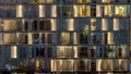 Windows of the multi-storey building of glass and steel lighting inside and moving people within timelapse Royalty Free Stock Photo