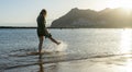 Bliss Teenager splashing while kick the water with the leg, having fun in the sea walking in the sunset. Lady laugh and splash