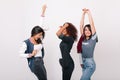 Blissful asian girl with arm tattoo standing with hands up and smiling while her friends dancing. Happy latin girl in Royalty Free Stock Photo