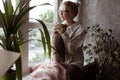 Blissful, calm, pensive young blond woman in eyeglasses look out window with hot tea. Relocation, new life and moving Royalty Free Stock Photo