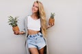 Blissful fair-haired lady posing with exotic fruits. Debonair tanned female model holding pineapple