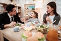 Blissful family eating dishes at table together. Parents with their daughter gathered at table.