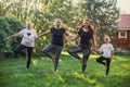 Blissful females of four generations of one family standing on one leg holding each other hands warming up on meadow Royalty Free Stock Photo