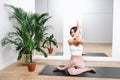 Blissful woman doing yoga at home. Sitting in a cow pose with intertwined hands Royalty Free Stock Photo