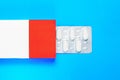 blister pack with pills in a red-white box on a blue background. copy space. Royalty Free Stock Photo