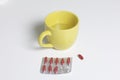 Blister with red pills. Several pills are missing. Nearby there is a mug with water and one pill for use. Royalty Free Stock Photo