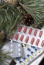 The blisters with pills. Different colors. Spruce and pine branches with cones. On a wooden box Royalty Free Stock Photo