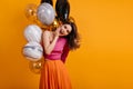 Blithesome birthday girl posing with smile. Lovable lady standing on yellow background with party balloons