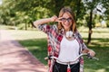 Blithesome girl in big headphones riding around park. Outdoor photo of laughing adorable lady sitti