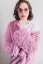 Blithesome young woman in trendy round glasses standing on white background. Studio shot of jocund