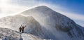 Blizzard in the mountains. Hikers returning happy on the ridge after reaching the summit in a strong foehn wind, the so-called