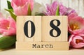 Block calendar with date 8th of March and tulips on table against background. International Women`s Day Royalty Free Stock Photo