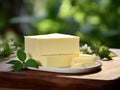 A block of fresh, creamy butter sits on a wooden board garnished with green leaves, embodying wholesome simplicity