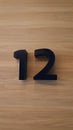 Block number twelve on a brown wooden wall background. Numeric sign or symbol. Royalty Free Stock Photo