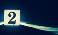 Block with number 2, two, exposed on dark blue background Royalty Free Stock Photo