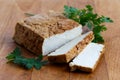 Block of smoked tofu, two tofu slices and fresh parsley on wood