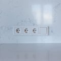 Block of three sockets and a switch on a white wall Royalty Free Stock Photo