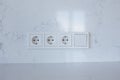 Block of three sockets and a switch on a white wall Royalty Free Stock Photo