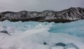 The block of turquoise ice hummocks is covered with snow.