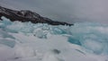 A block of turquoise ice hummocks lies in disarray on the snow.