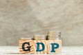Block in word GDP (Gross domestic product) with coin in increase trend on wood background
