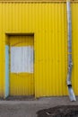 blocked entrance to a yellow colored building next to a drain pipe