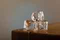 3 blocks of ice melting on a oak table, with a blue shined background on a grey surface. With dipping water from the table