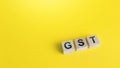 Blocks with letters GST Goods and Services Tax on a yellow background. State financial policy to regulate tax collection rules