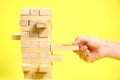 Blocks of the wooden game jenga on a yellow background, space for text Royalty Free Stock Photo