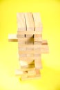 Blocks of the wooden game jenga on a yellow background, space for text Royalty Free Stock Photo