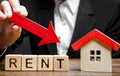 Blocks with the word Rent, down arrow and a miniature house. The concept of reducing the price of renting a house or apartment.