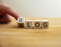 Blog VS vlog concept. Finger flips letter at wooden cube changing the word blog text to vlog video