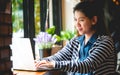 Blogger, Asian Women`s writers are using laptops at the coffee shop to write, share stories or travel reviews to her social media