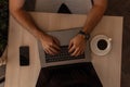 Blogger businessman guy working on a modern laptop in a office. Top view on wooden desktop with laptop with cup of coffee with