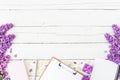 Blogger or freelancer workspace with clipboard, notebook, pen, lilac, box and petals on wooden background. Flat lay, top view. Bea