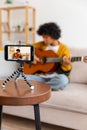 Blogger guitarist. Happy african american girl blogger playing guitar singing song recording vlog. Social media Royalty Free Stock Photo