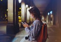 Blogger hipster using in hands gadget mobile phone, woman with backpack pointing finger on blank screen smartphone on background b Royalty Free Stock Photo