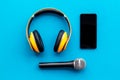 Blogger, journalist or musician office desk with mobile phone, microphone and headphones on blue background top view