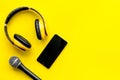 Blogger, journalist or musician office desk with mobile phone, microphone and headphones on yellow background top view