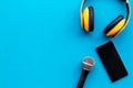 Blogger, journalist or musician work space with microphone, telephone and headphones on blue background top view mock-up