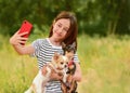 Girl with animals makes a selfie on a smartphone. The blogger shoots a video with chihuahua dogs