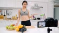 Blogger sporty Asian woman using camera recording how to make apple juice video for her subscriber, female use organic fruit